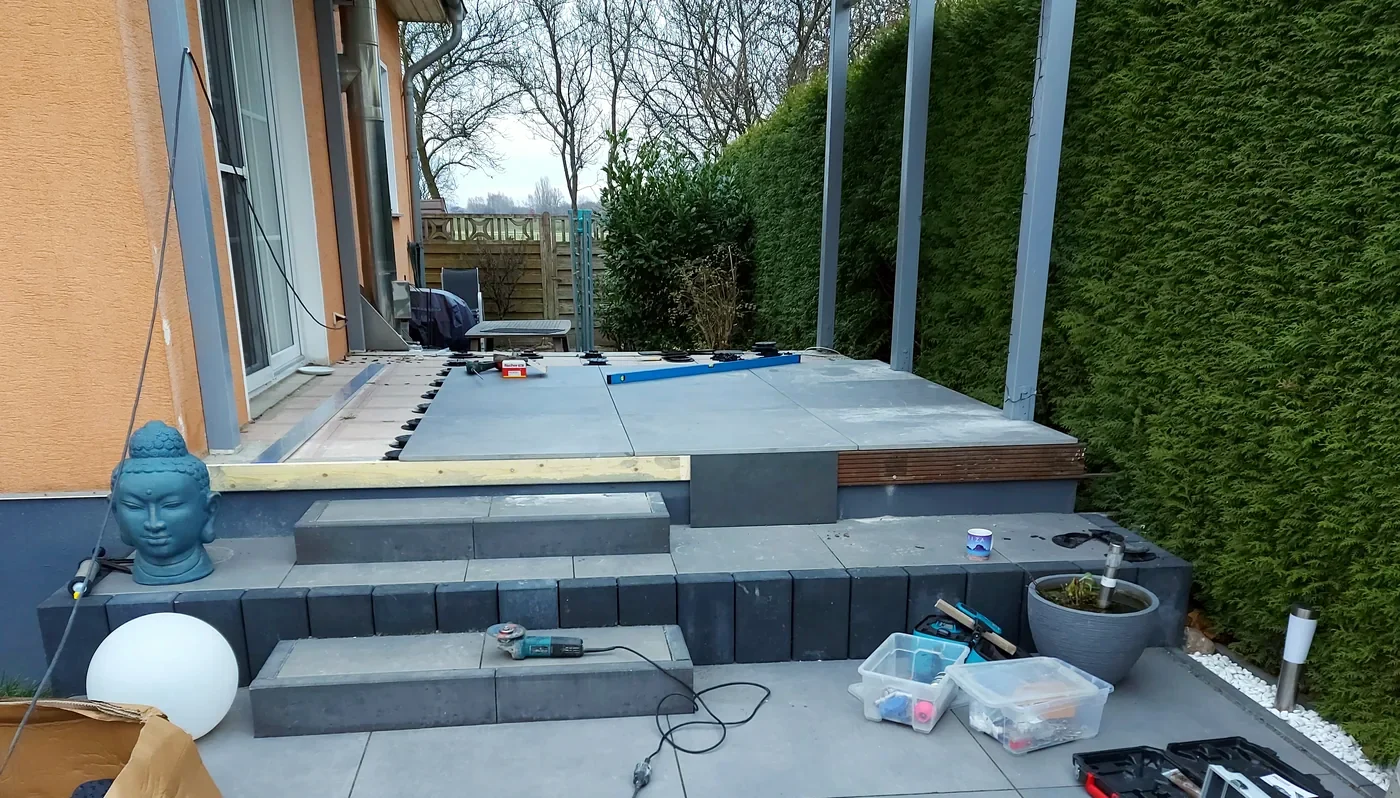 Beleuchtete Terrassentreppe aus dunklen Blockstufen mit hellen Feinsteinzeugplatten bei Nacht