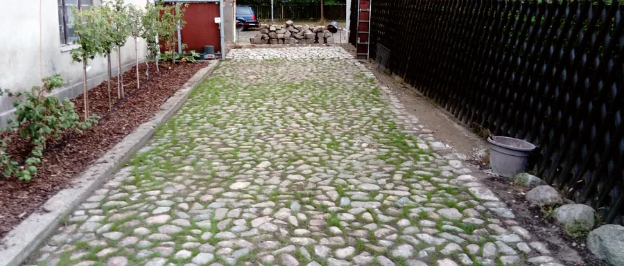 Einfahrt aus Natursteinpflaster mit begrünten Fugen