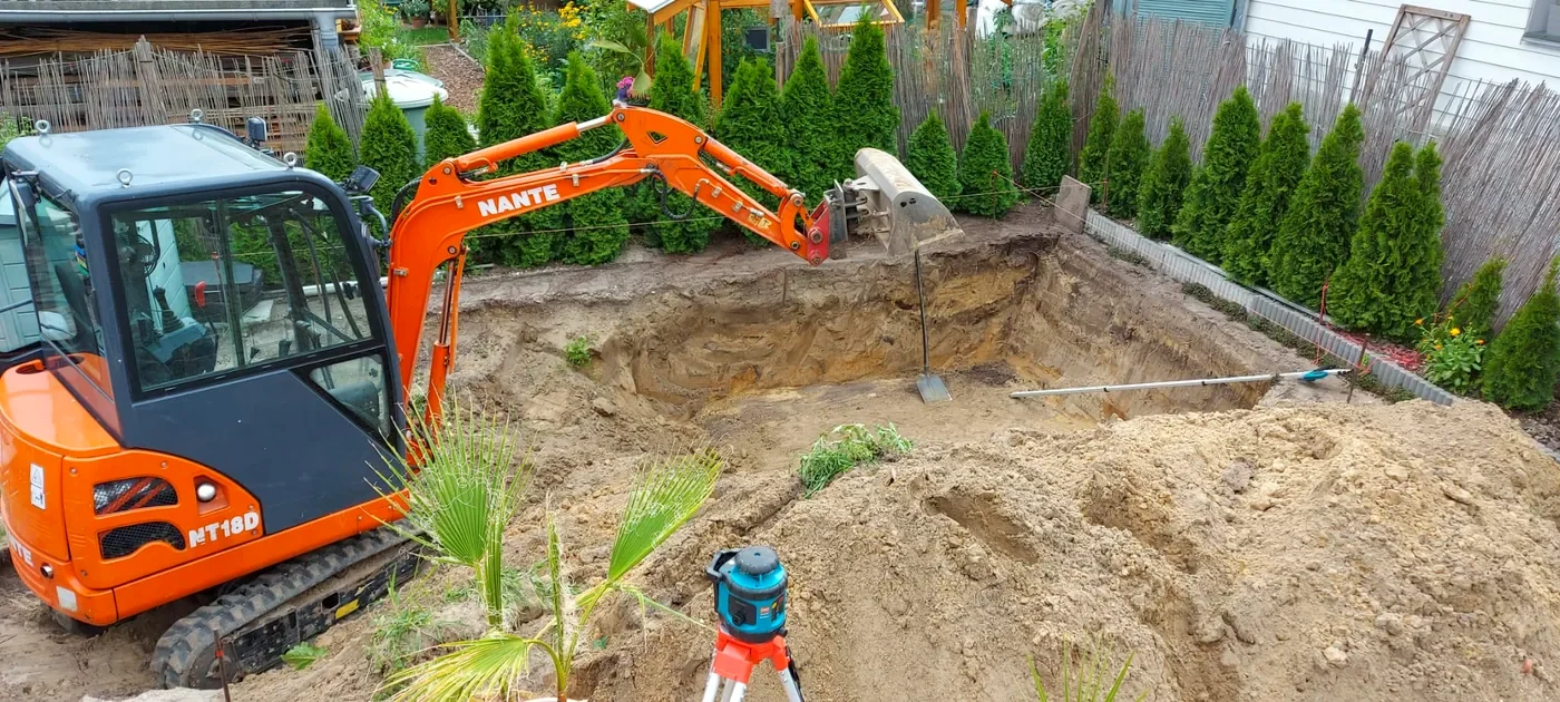 Minibagger beim Aushub der Poolgrube im Garten