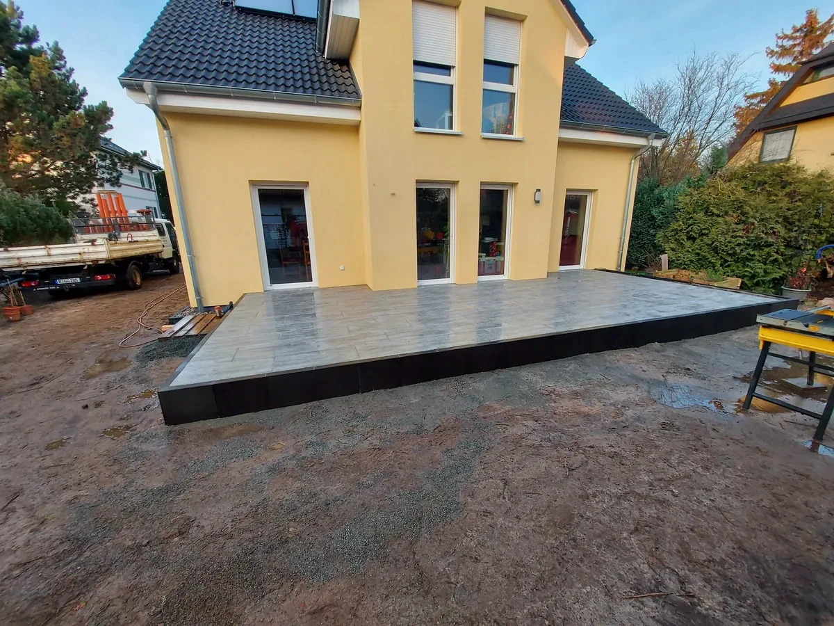 Hochterrasse mit großformatigen Platten an einem gelben Wohnhaus in Berlin-Biesdorf