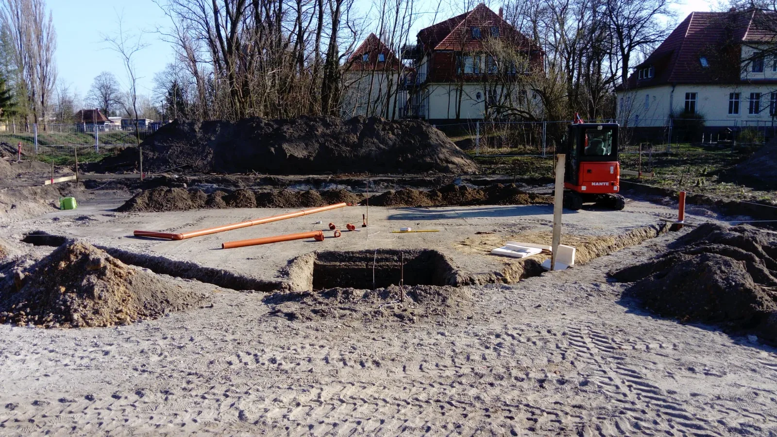 Ausgehobene Frostschürze mit verlegten Grundleitungen auf einem Baugrundstück