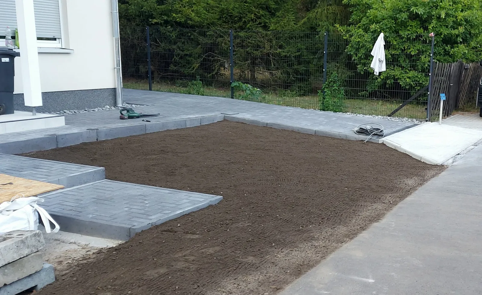 Gepflasterte Fläche mit Gehwegüberfahrt und vorbereitetem Rasenplanum