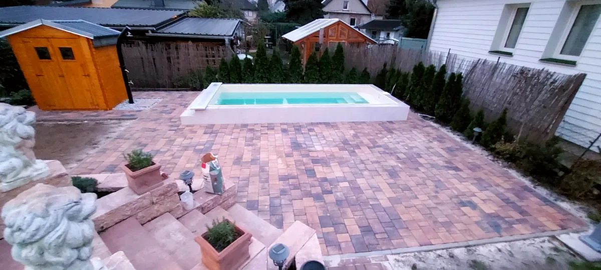 Fertiger Pool mit umlaufender Pflasterterrasse und Außendusche