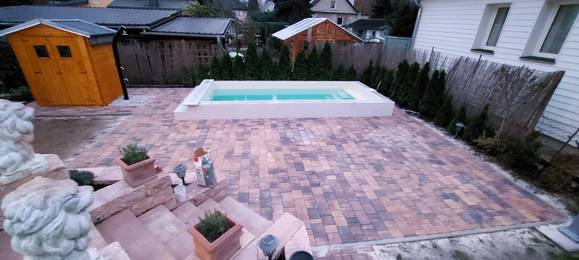 Fertiger Pool mit umlaufender Pflasterfläche im Farbmix und Gartenhaus