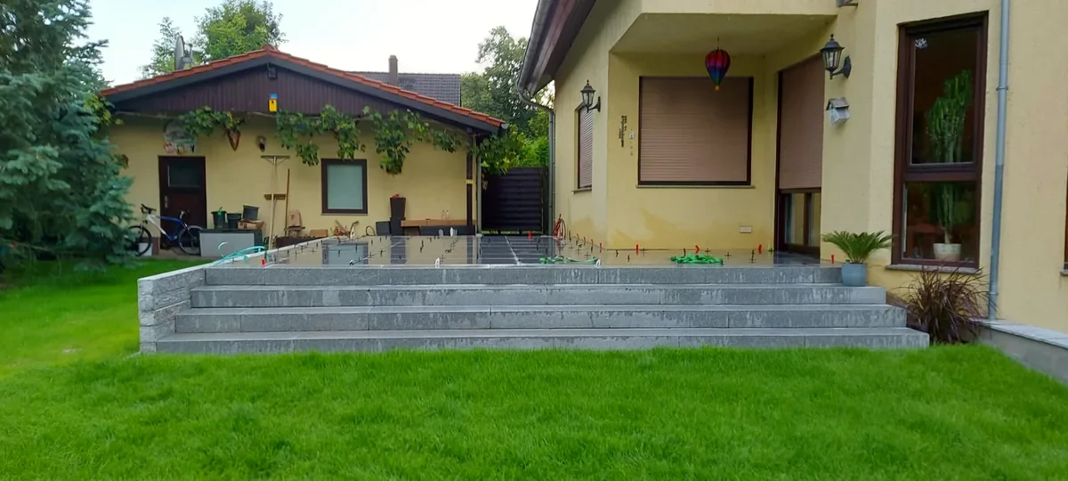 Erhöhte Terrasse mit Granitstufen und Stützmauer nach einer Poolsanierung