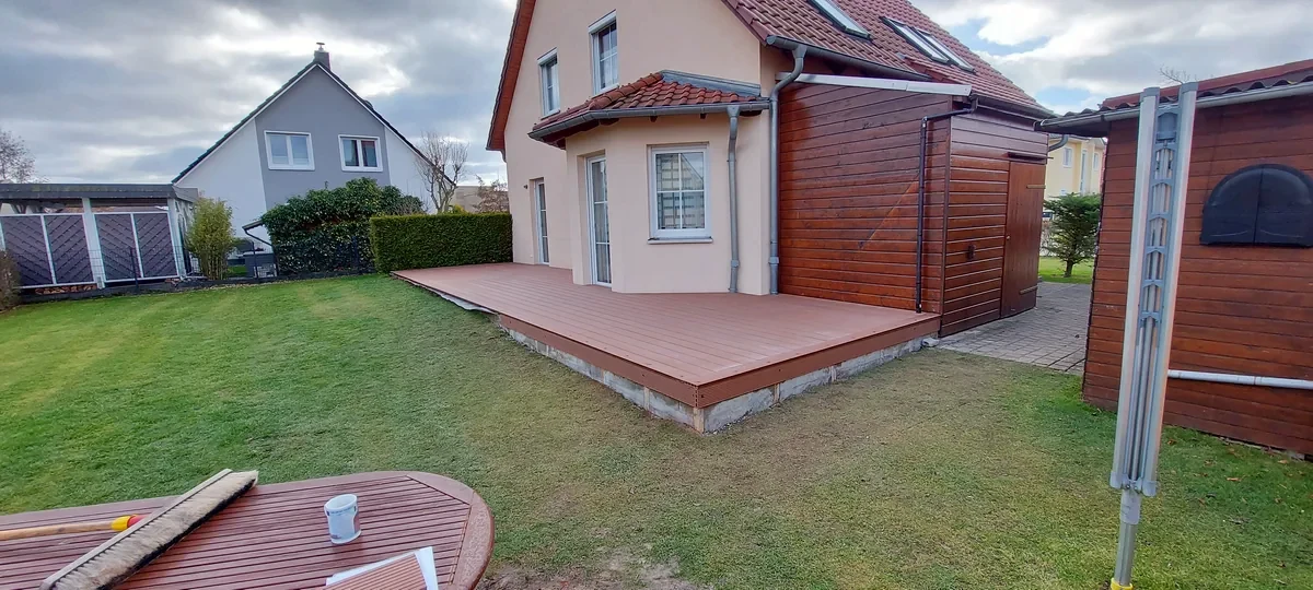 Fertige WPC-Terrasse an einem Einfamilienhaus mit angrenzender Rasenfläche